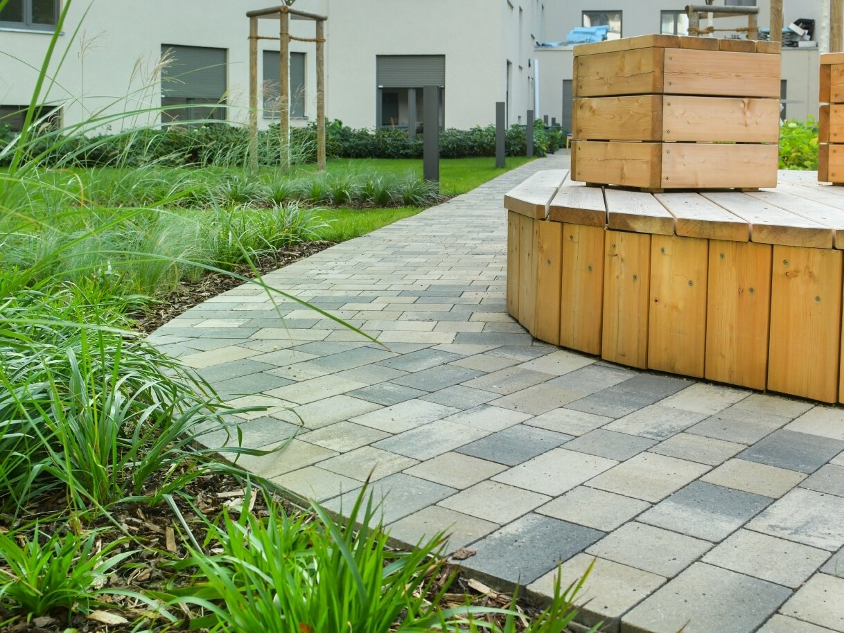 Außenansicht degewo-Neubau Klara-Franke-Straße 1 bis 7: Hofseite mit Sitzgelegenheiten auf Erhöhung und Beet im Vordergrund.