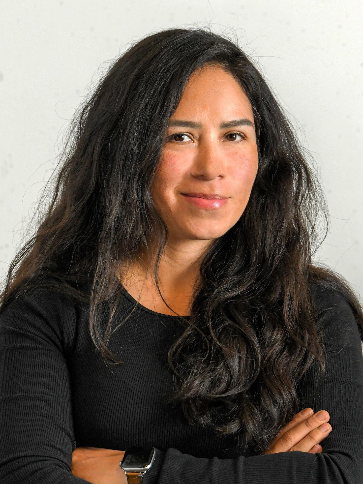Porträt des Mieterbeiratsmitglieds Liliana Vazquez mit verschränkten Armen vor neutralem Hintergrund