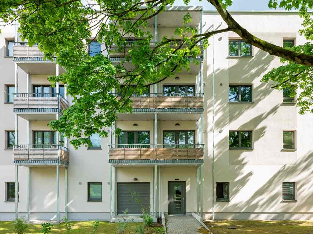 Außenansicht degewo-Neubau Färberstraße 19A mit Balkonen, im Vordergrund oben beblätterter Ast.