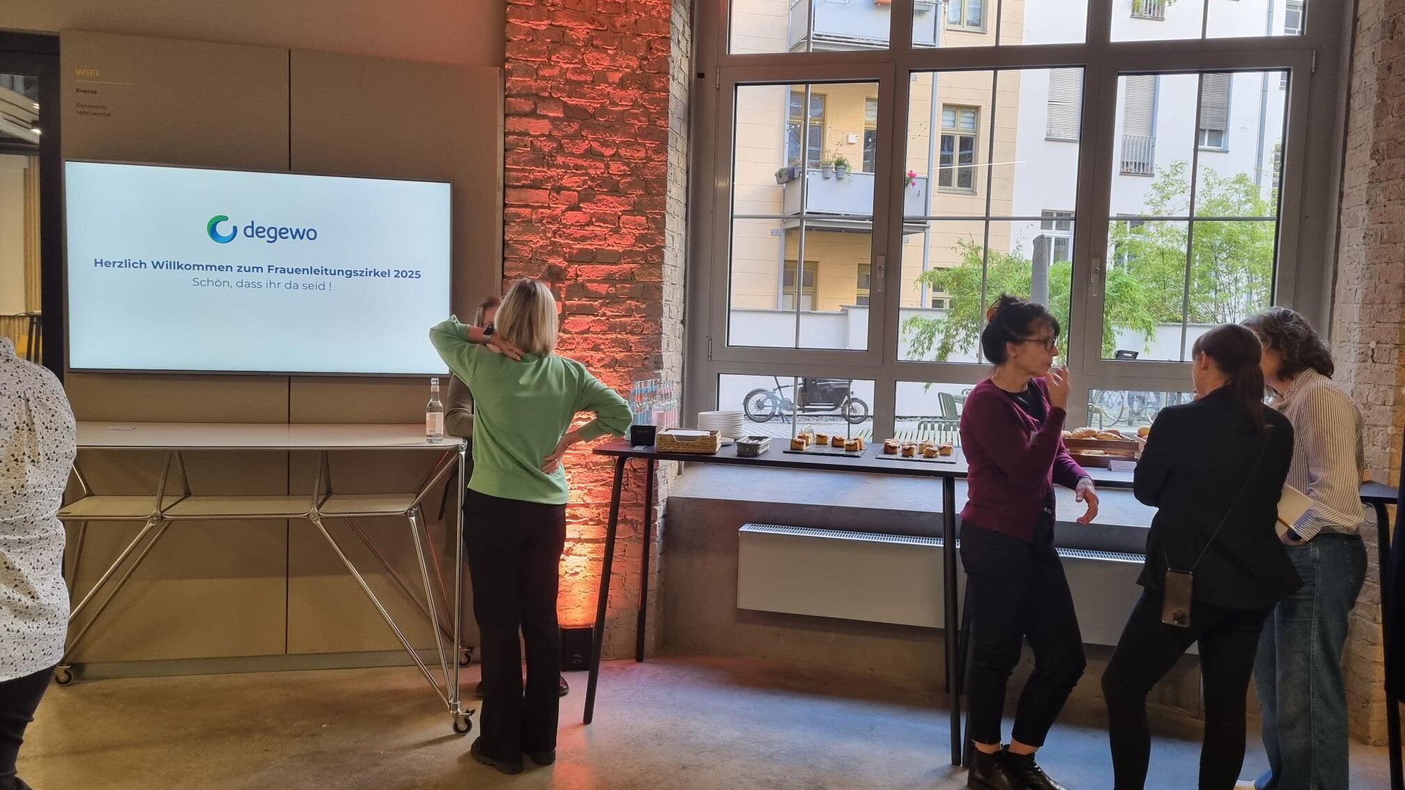 Teilnehmerinnen stehen im Raum und unterhalten sich beim Empfang.