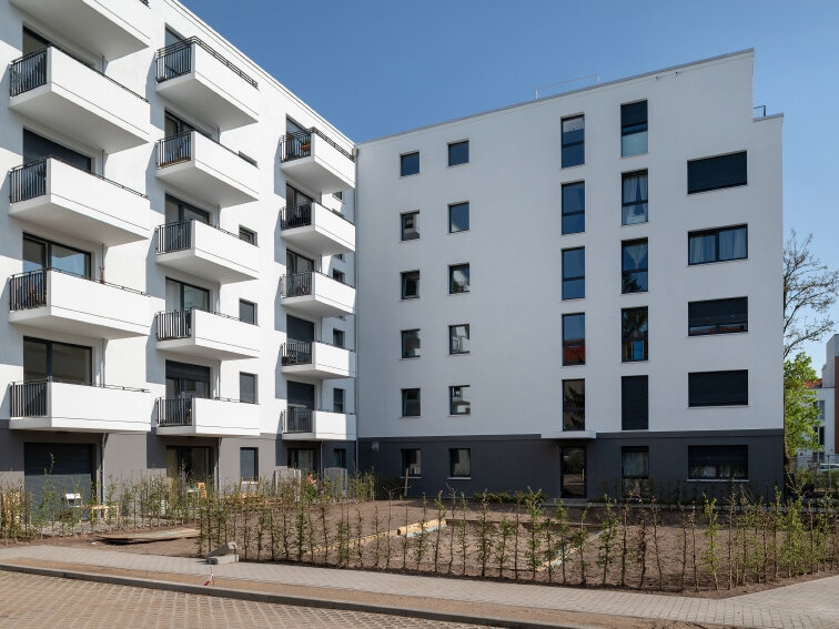Außenansicht degewo-Neubau Bendastra0e 11 C mit Parkflächen und Gehweg im Vordergrund.