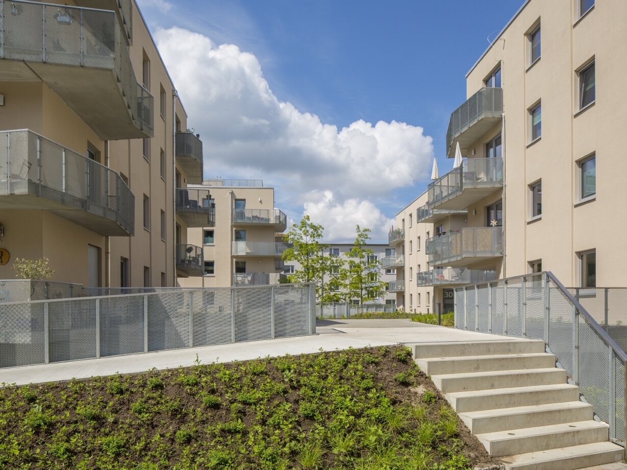 Außenansicht degewo-Neubau Karl-Pokern-Straße 30 bis 36 mit Hang und Treppe im Vordergrund.