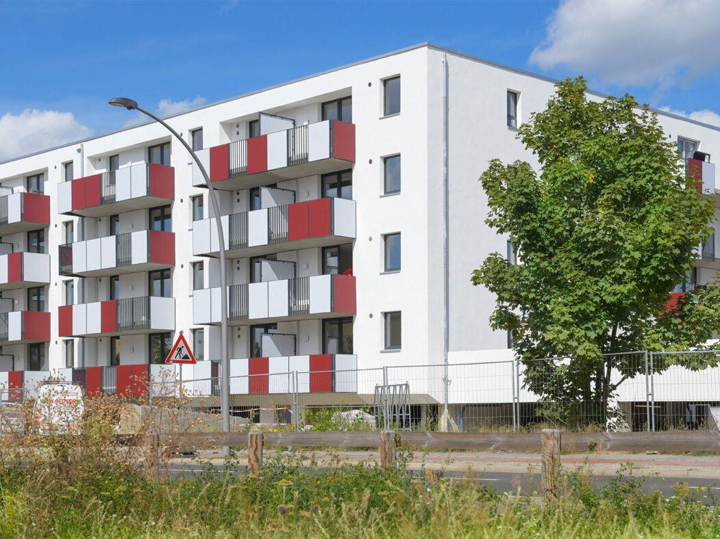 Außenansicht degewo-Neubau Schönefelder Chaussee 26 bis 38 Wegedornstraße 119 bis 123 mit Grünfläche und Straße im Vordergrund.