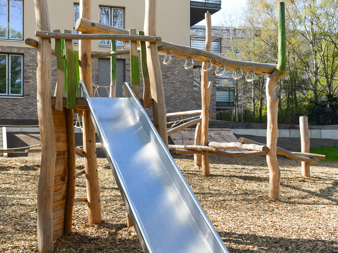 Außenansicht degewo-Neubau Pulsstraße 13 und 15: Hofseite mit Spielplatz, Rutsche im Vordergrund.