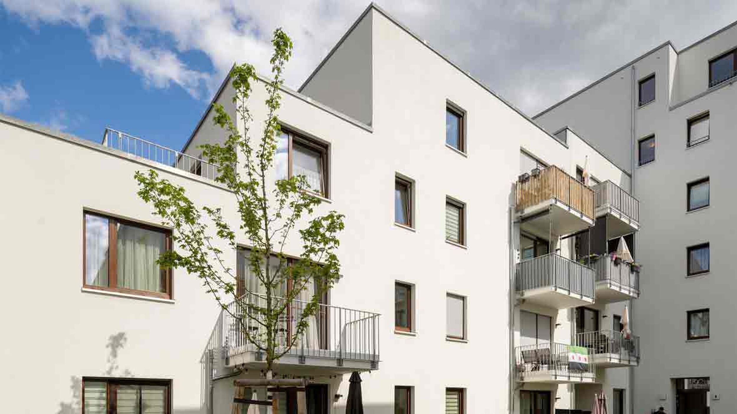 Außenansicht degewo-Neubau Glasower Straße 3 A mit neu gepflanztem Baum im Vordergrund.