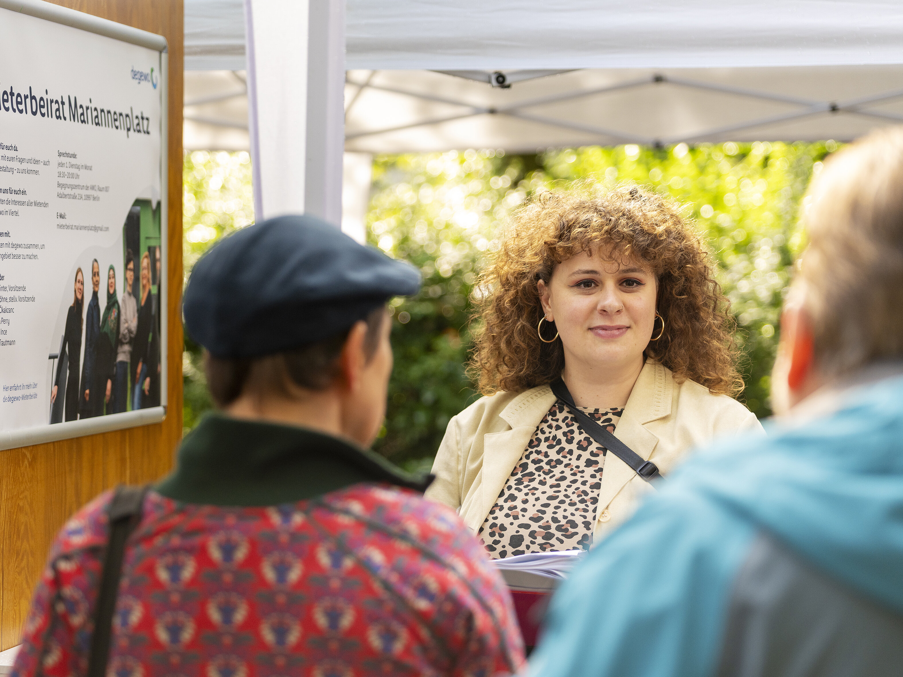 Gesprächssituation am Informationsstand: Eine Mitarbeiterin im Austausch mit Anwohnenden vor einer Tafel des Mieterbeirats Mariannenplatz.