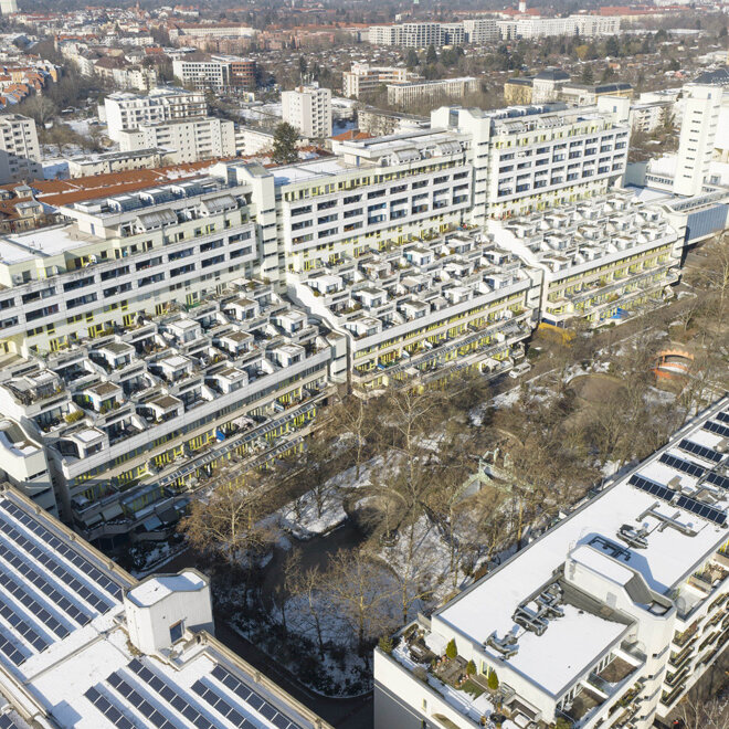 Luftaufnahme der Schlangenbader Straße in Berlin mit den markanten terrassenförmigen Wohngebäuden und verschneiten Dächern, umgeben von Stadtvierteln und Straßen.