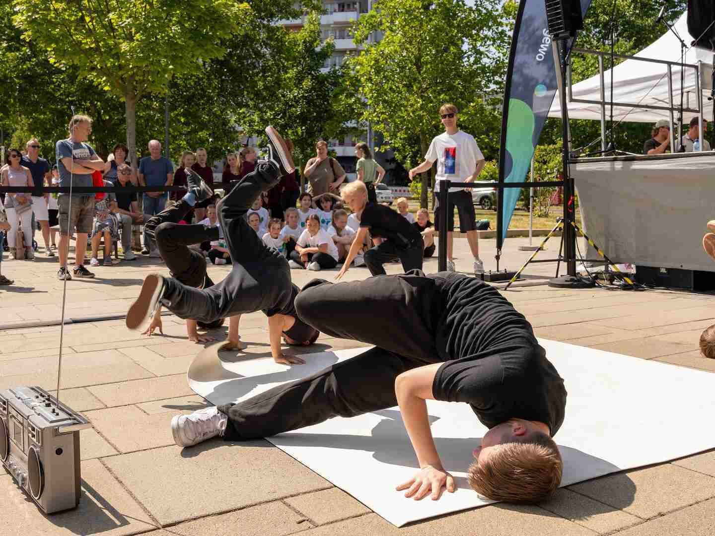 Breakdancer vollführen Tricks vor einer Bühne.