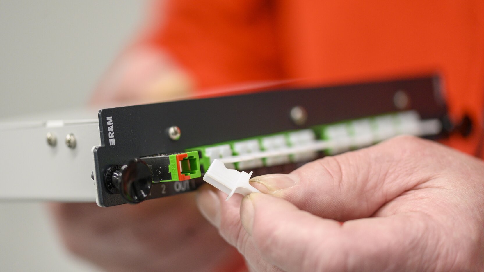 Zwei Hände halten eine Einschub-Glasfaser-Komponente.