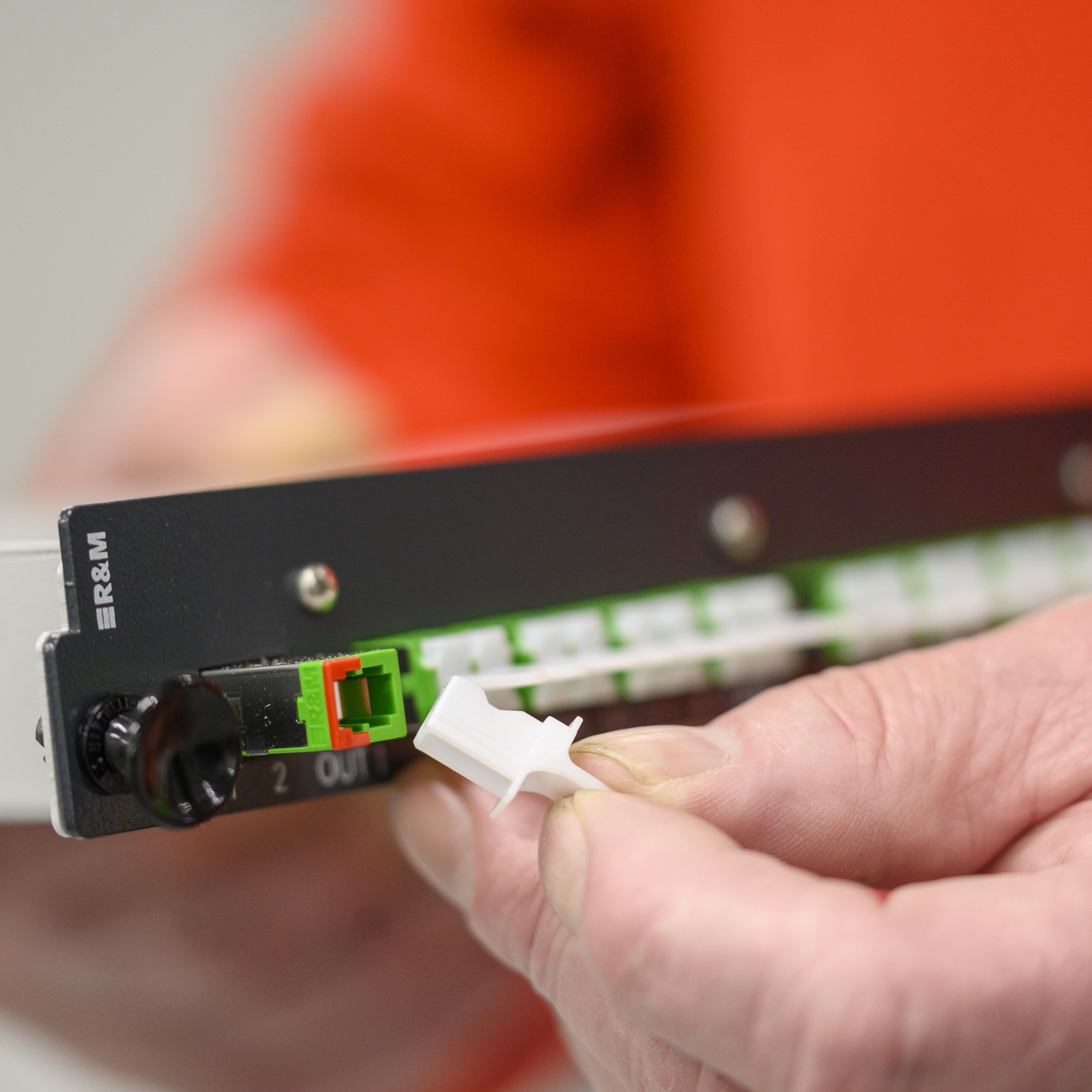 Zwei Hände halten eine Einschub-Glasfaser-Komponente.