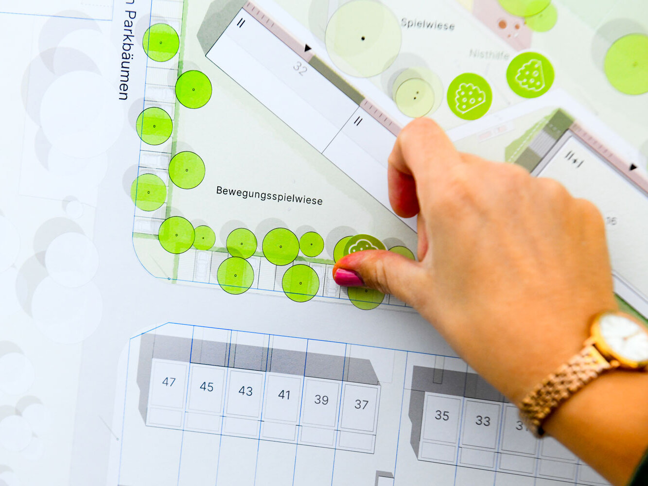 Eine Hand klebt Klebepunkte auf einen Bebauungsplan.