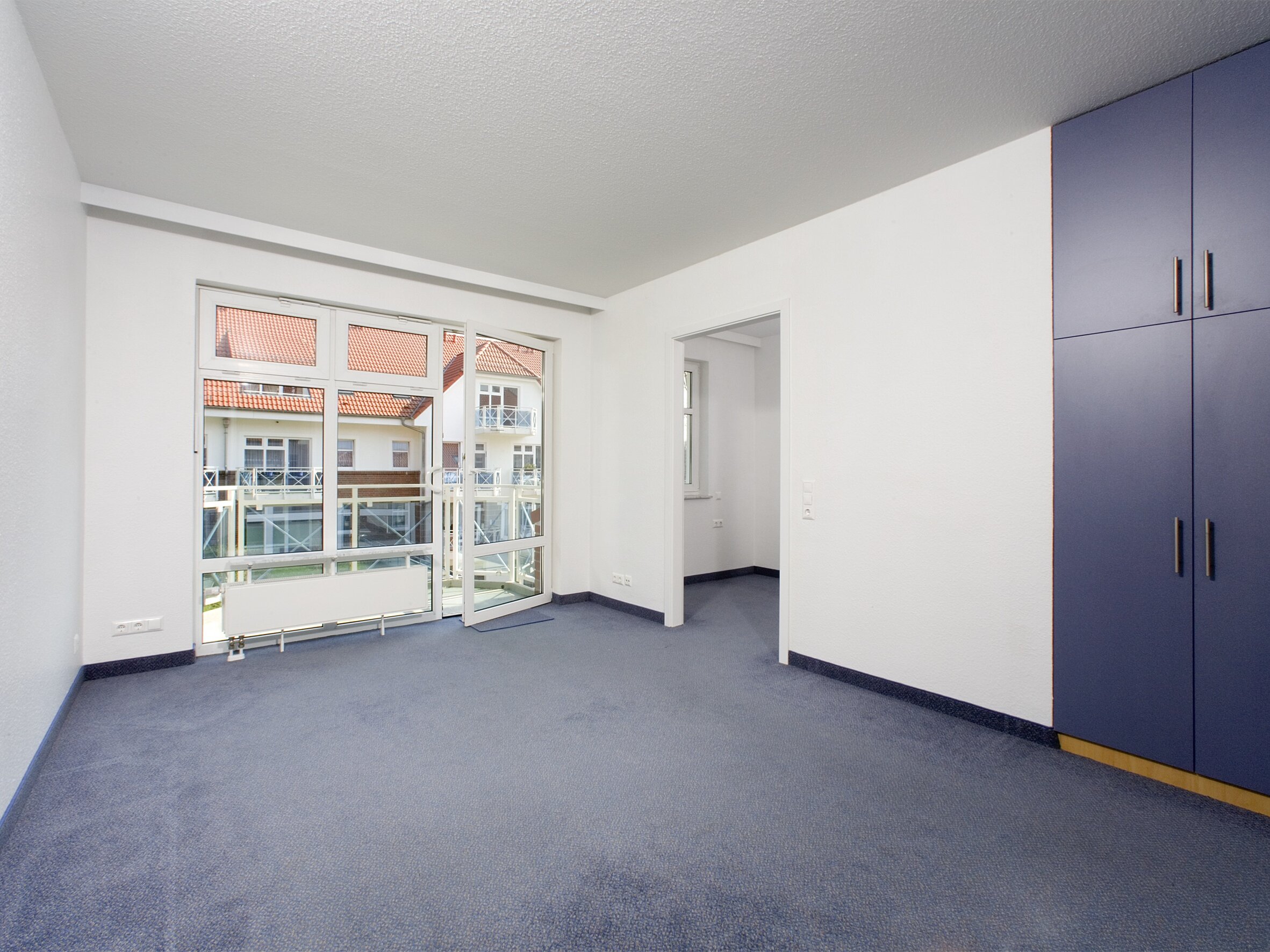Ein leerer Raum mit blauem Teppich und Wandschrank.