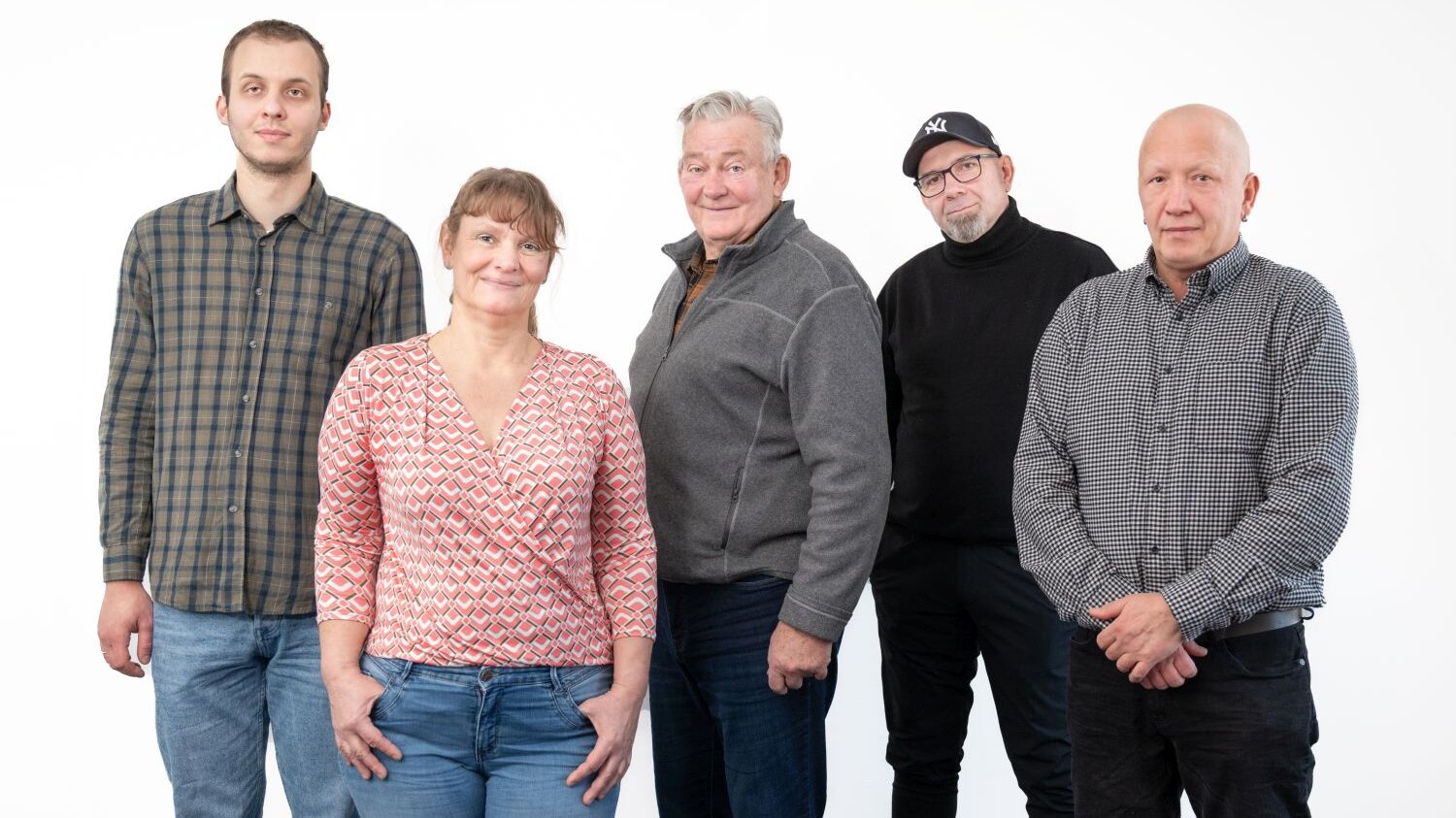 Fünf Menschen stehen vor einer weißen Wand nebeneinander und schauen in die Kamera. 