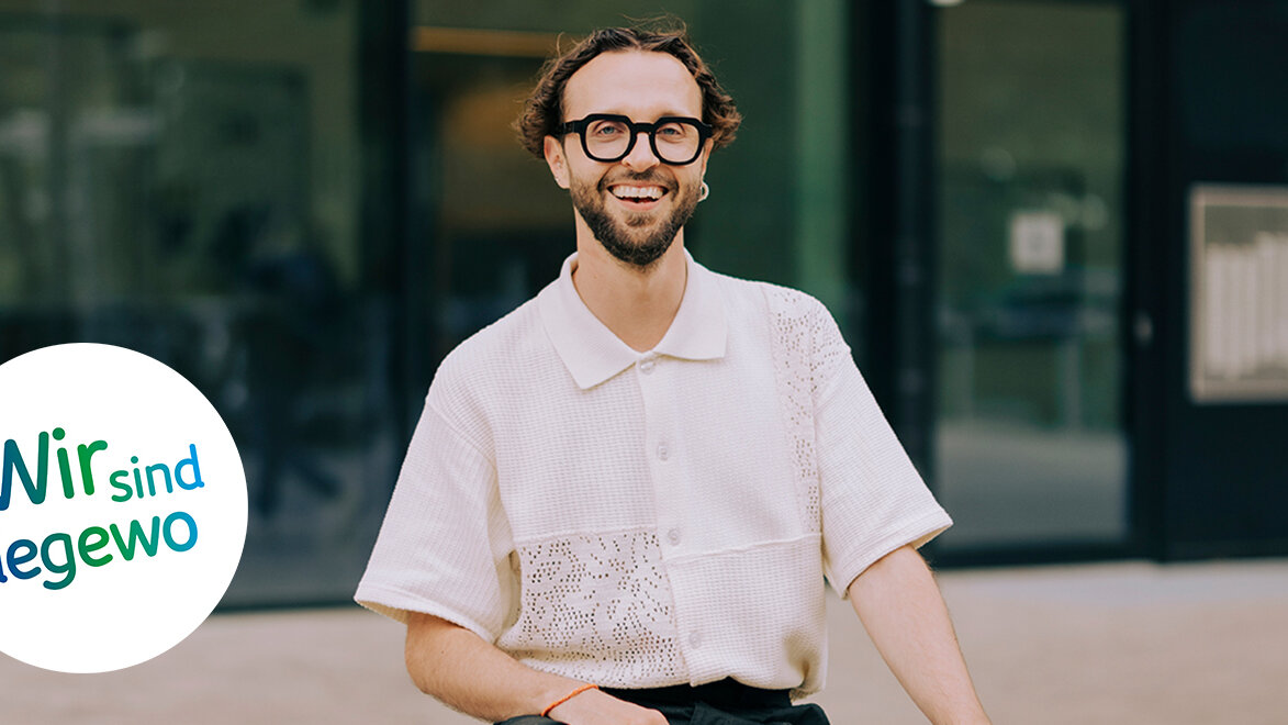 Ein Mann sitzt auf Betonblöcken auf einen Platz in der Gropiusstadt in Berlin und lacht in die Kamera.
