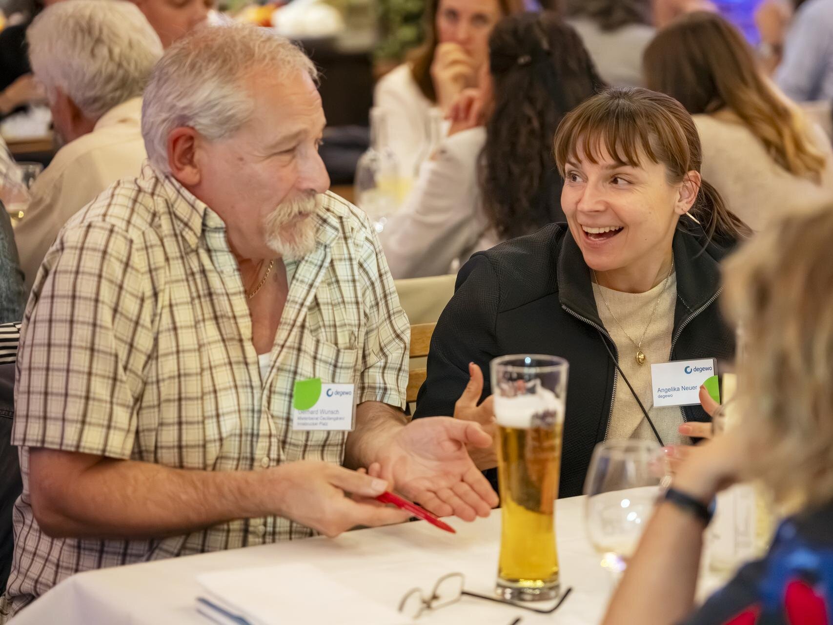 Zwei Gäste sitzen am Tisch, reden und lachen miteinander.