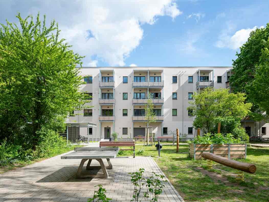 Außenansicht degewo-Neubau Färberstraße 19B mit Tischtennisplatte und Balancierbalken im Vordergrund.
