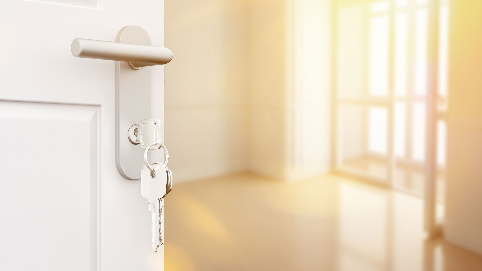 Nahaufnahme einer weißen Wohnungstür mit steckendem Schlüssel im Schloss; im Hintergrund ein heller, leerer Raum mit großen Fenstern – Symbolbild für Wohnungsübergabe oder Einzug.