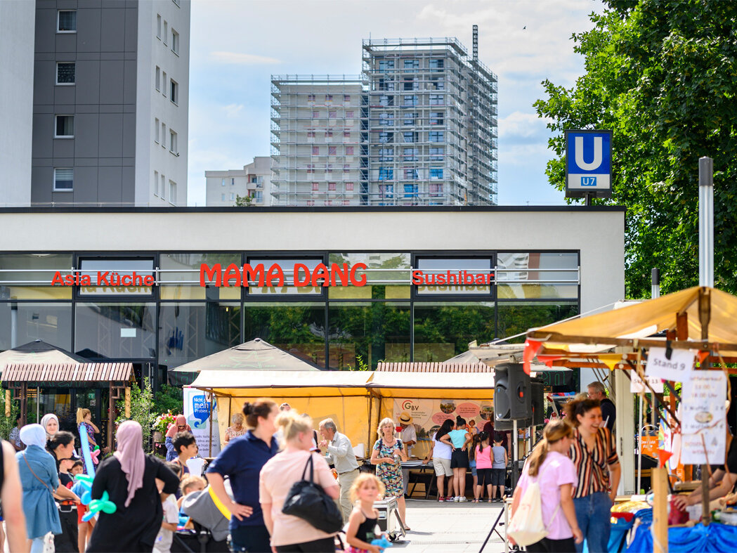 Menschen und gelbe Sonnenschirme vor dem Einkaufszentrum Wutzky