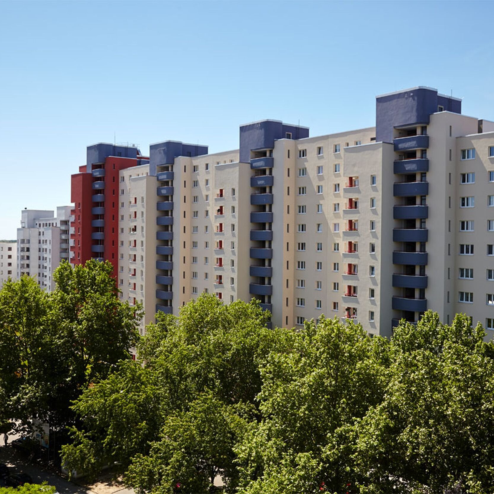 Außenansicht degewo-Ankauf Waldsassener Straße 11 und 16 bis 22 Lichtenfelder Ring 81 bis 89: Blick aus großer Entfernung mit Baumreihe im Vordergrund.