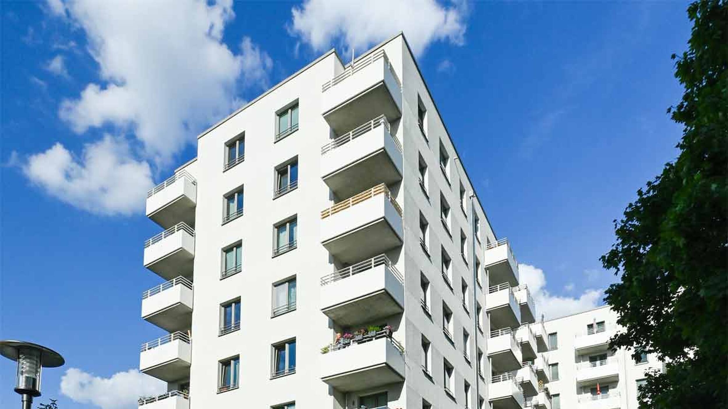 Außenansicht degewo-Neubau Borgenhagenweg 43A mit Straßenlaterne links, Weg und Fahrrad rechts im Vordergrund.