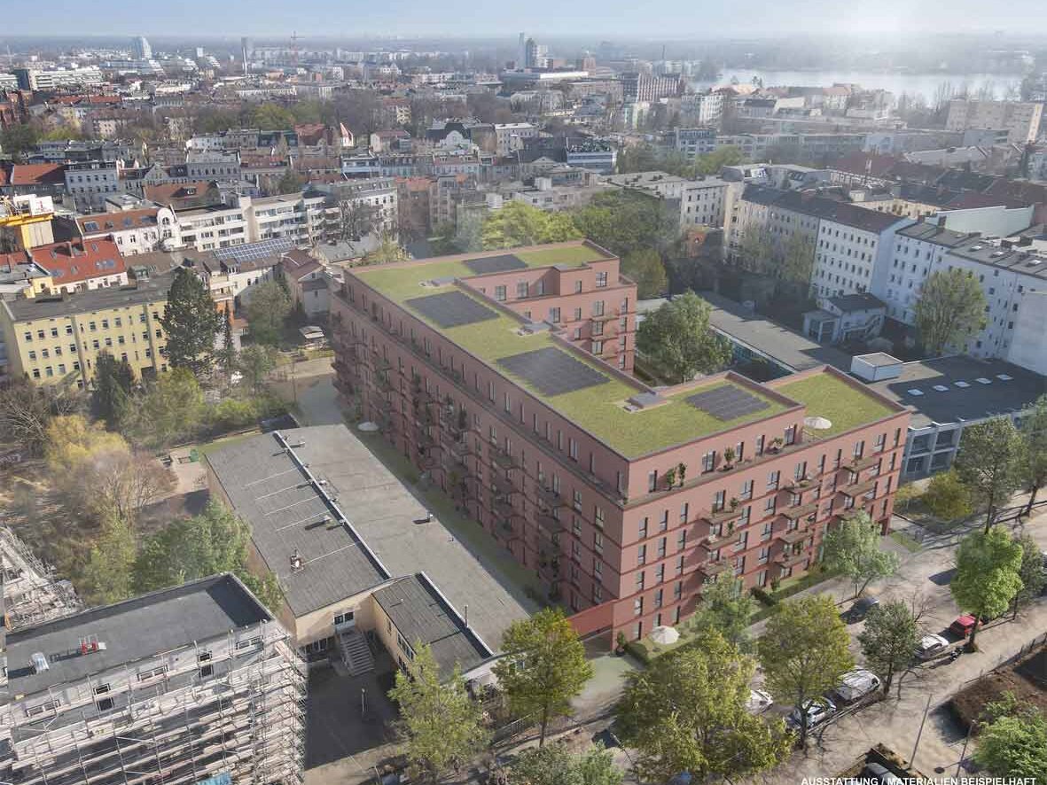 Luftperspektive eines sechsgeschossigen Neubaus mit roter Klinkerfassade und begrüntem Dach in innerstädtischer Lage. Balkone sind zur Hofseite ausgerichtet.