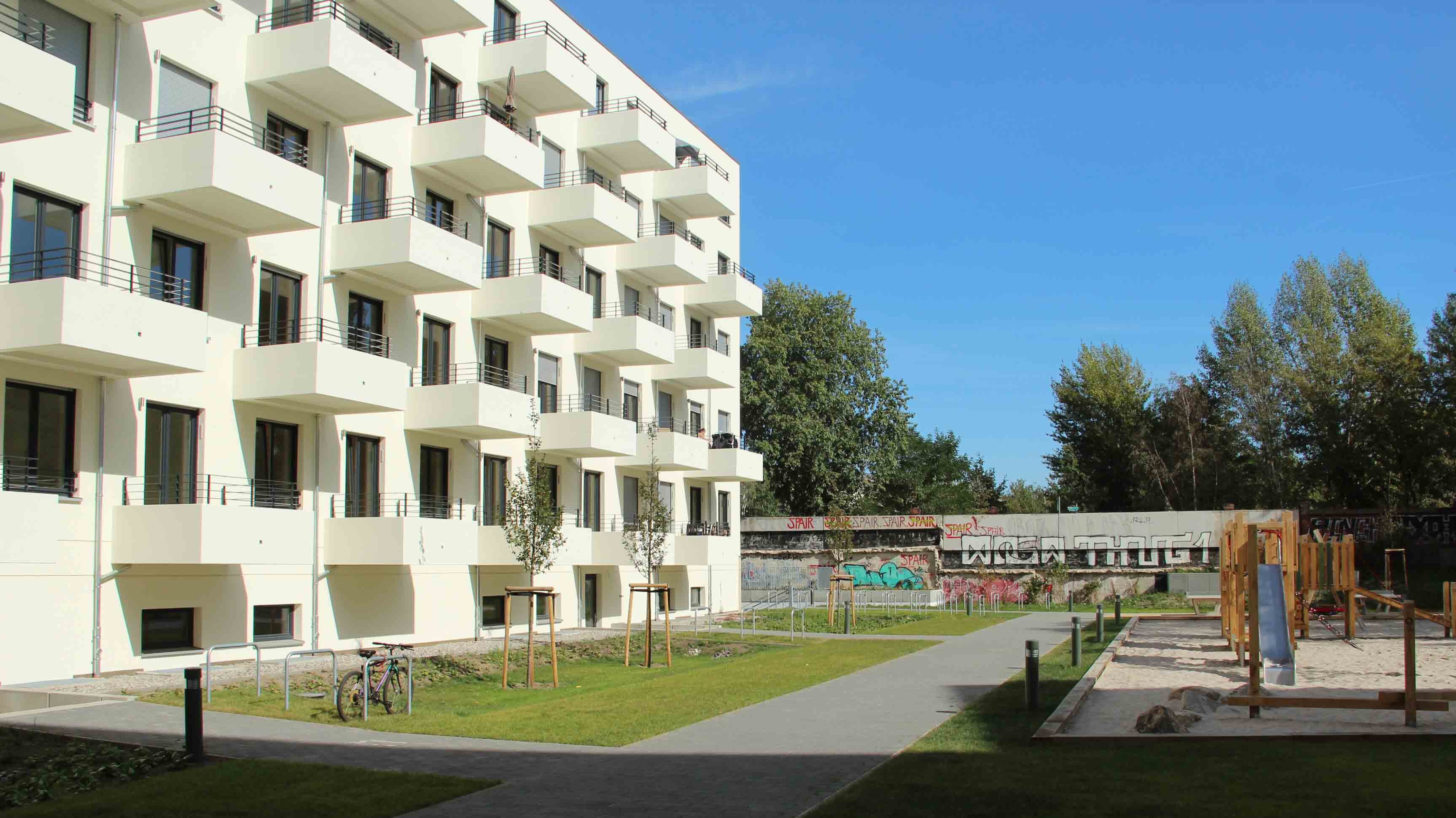 Außenansicht degewo-Neubau Graunstraße Gleimstraße: Hofseite mit Spielplatz sowie Wegen und Rasenflächen im Vordergrund.