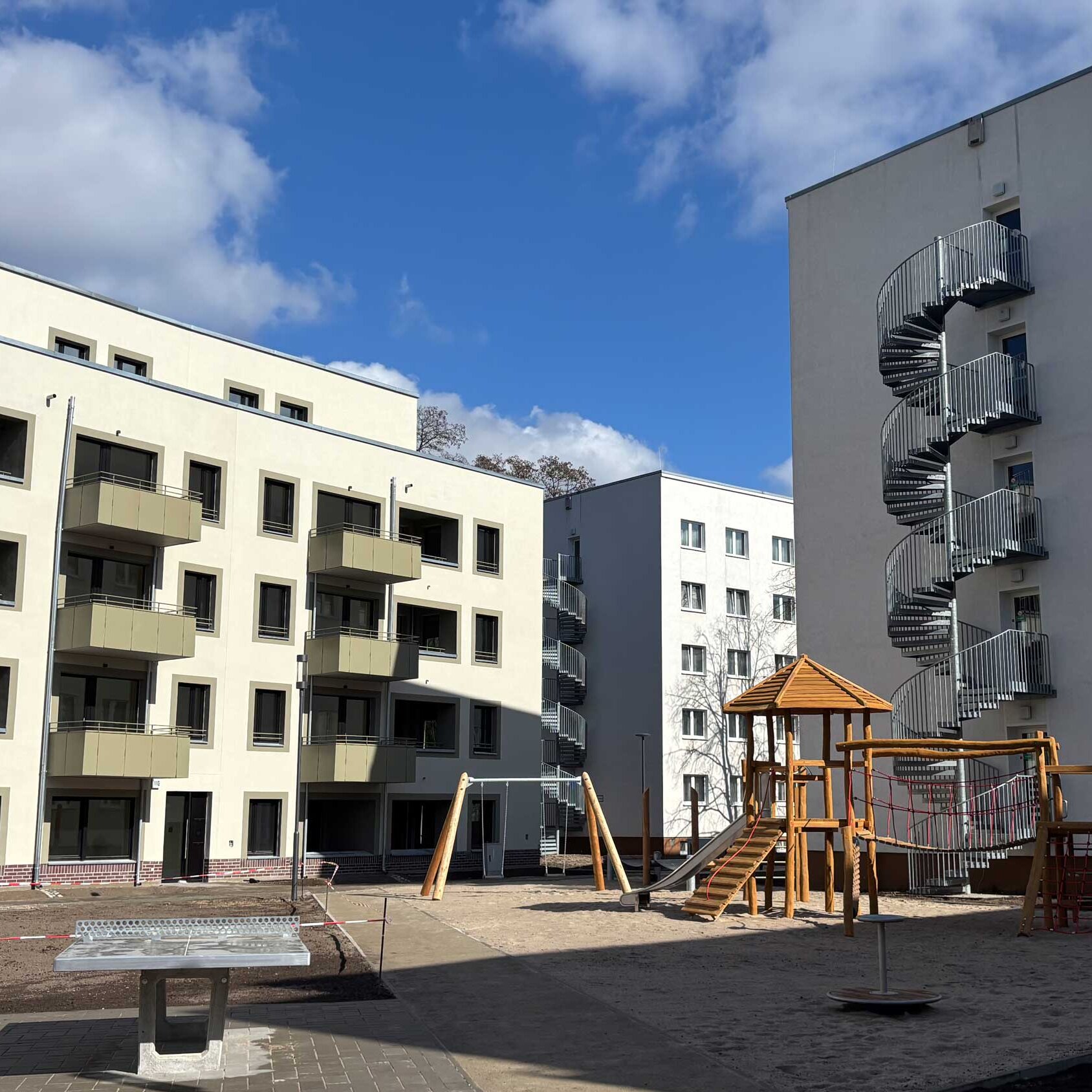 Außenansicht der Wohnanlage, mit Spielplatz und Tischtennisplatte. 