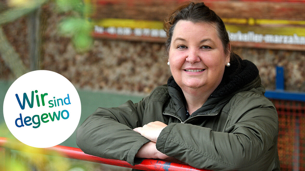 Eine Frau stützt sich auf ein Geländer und blickt freundlich in die Kamera.