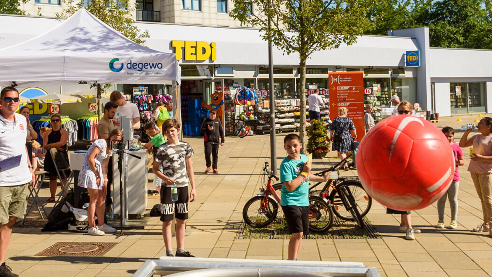 Kinder spielen Ball auf einem Platz vor Gebäuden