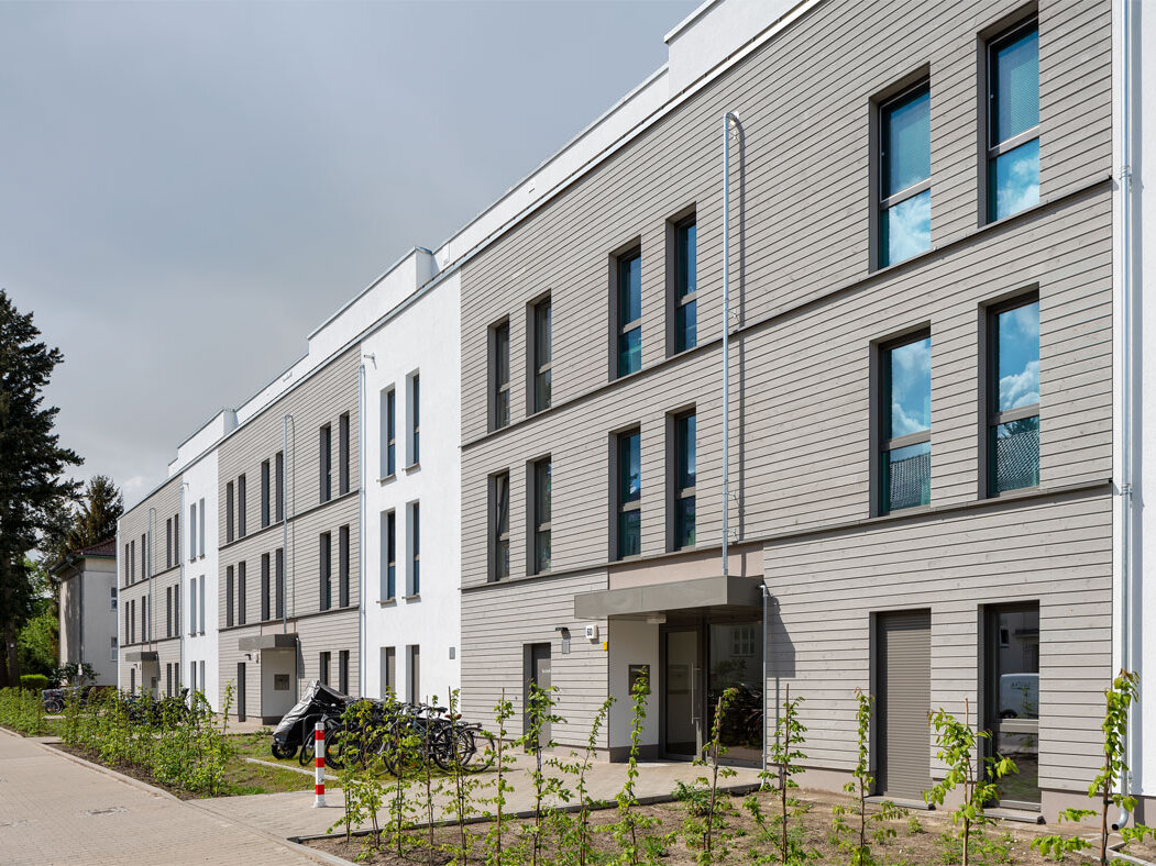 Außenansicht degewo-Neubau Stillerzeile 60 mit Wegen und Beeten vor dem Gebäude.