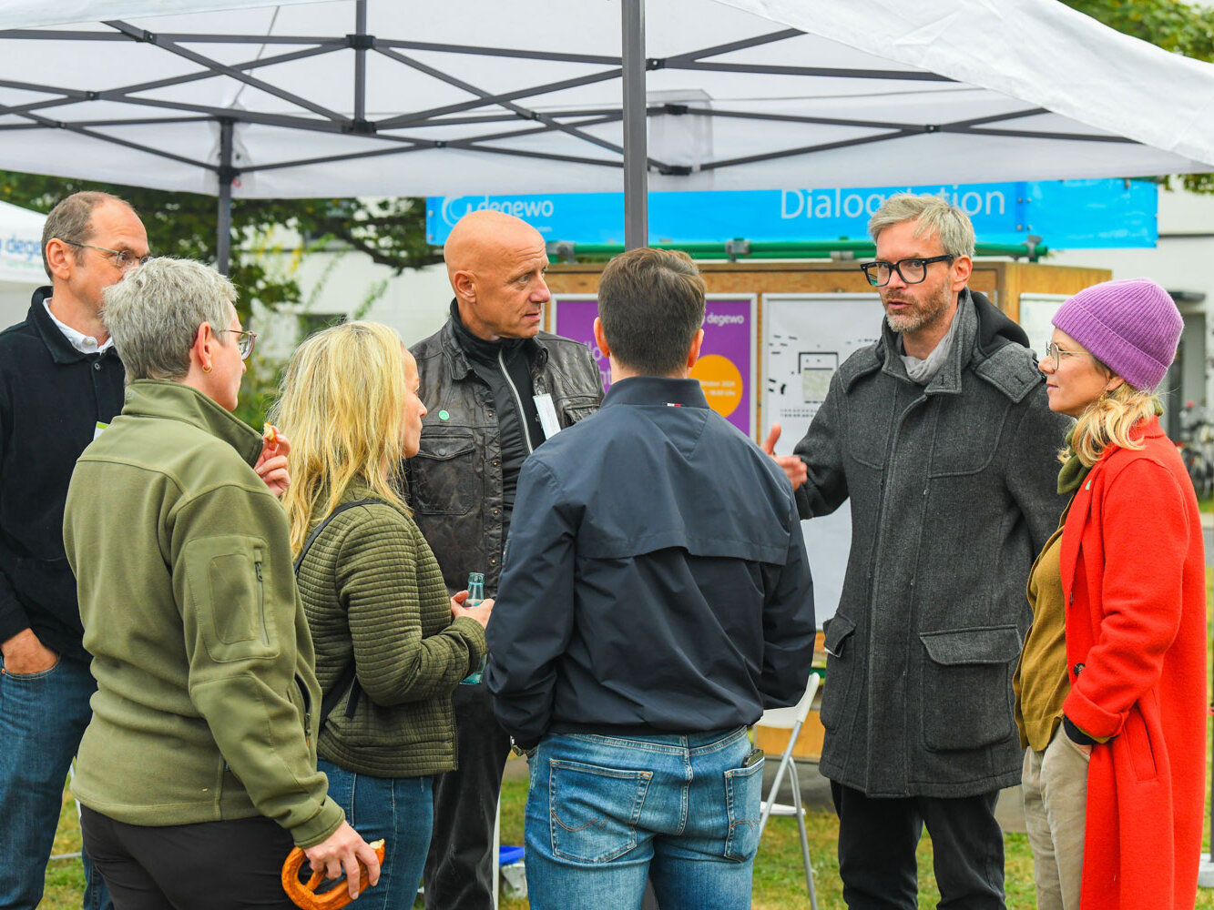 Mehrere Personen stehen als Gruppe zusammen und unterhalten sich.
