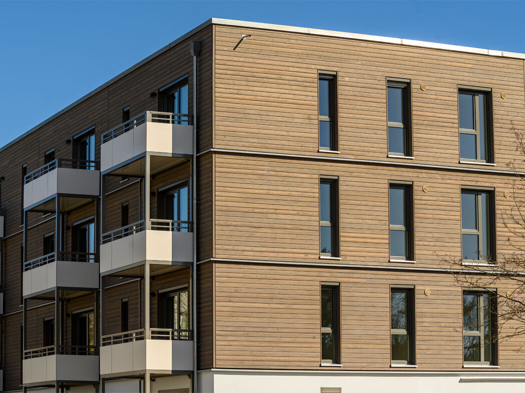 Außenansicht degewo-Neubau Am Omnibushof 2a mit unbeblätterten Baumzweigen rechts im Vordergrund.