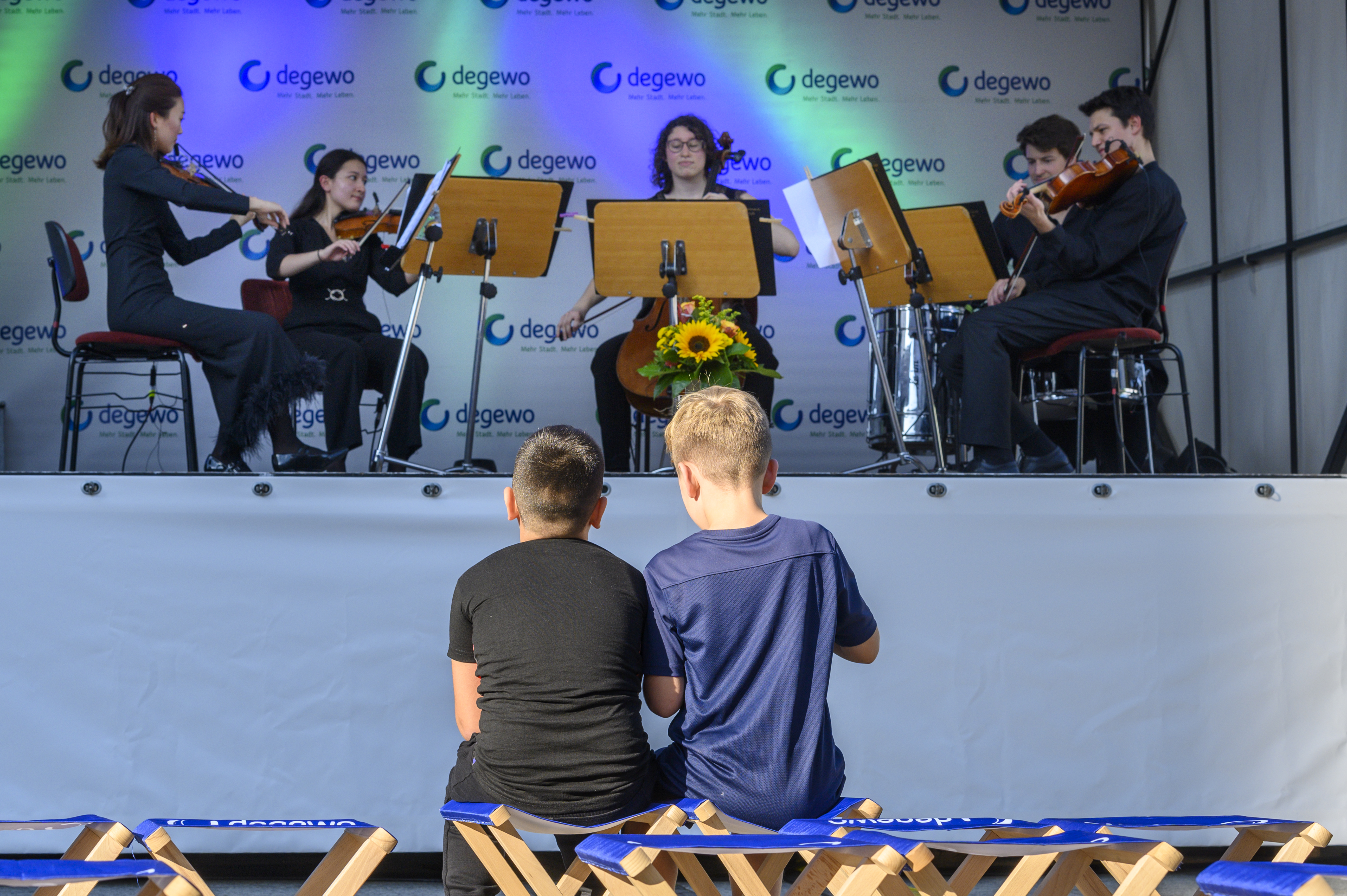 Kinder sitzen vor Bühne mit Musikern