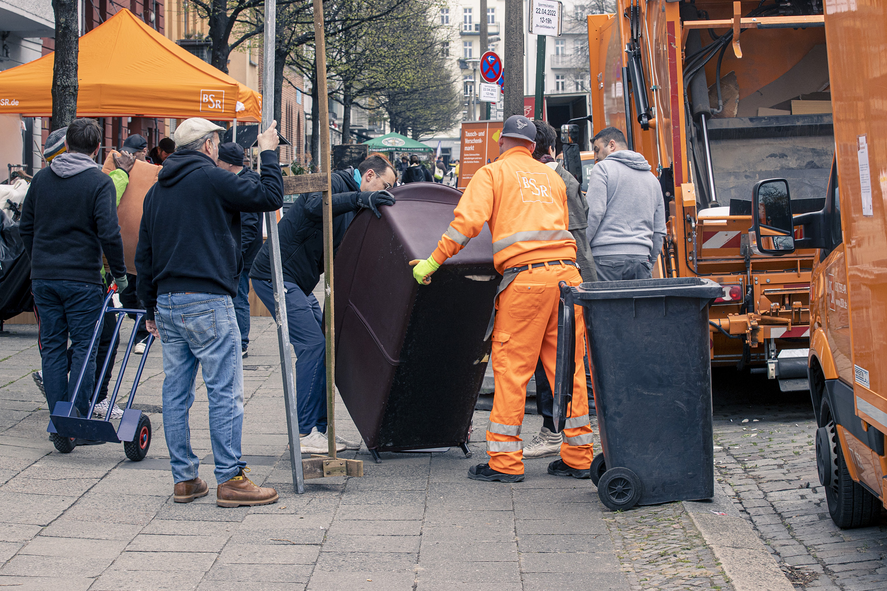 Mehrere Männer tragen Sperrmüll zu einem BSR Fahrzeug