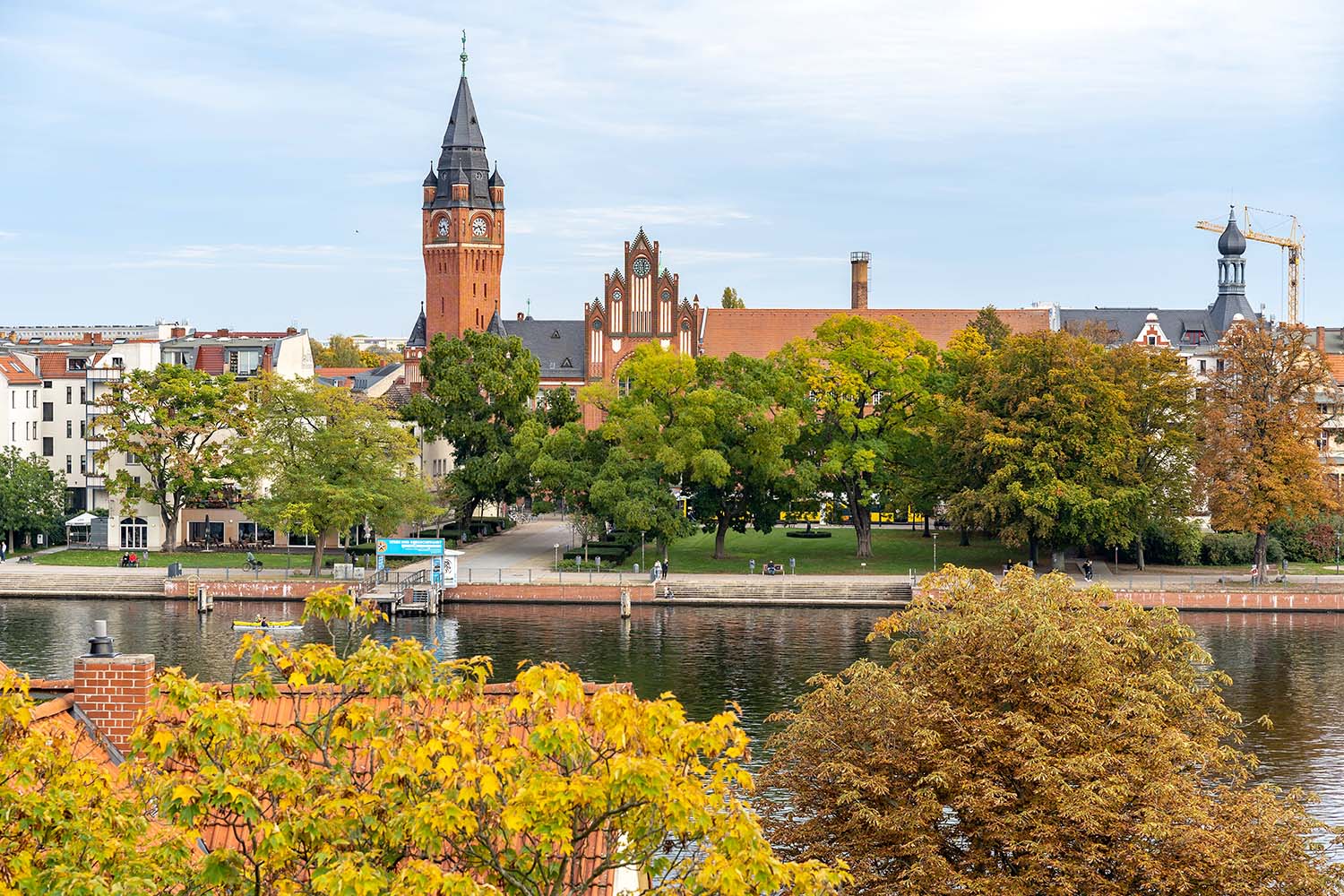 Blick über die Dahme auf das Rathaus Köpenick und die Uferpromenade mit Parkanlagen.