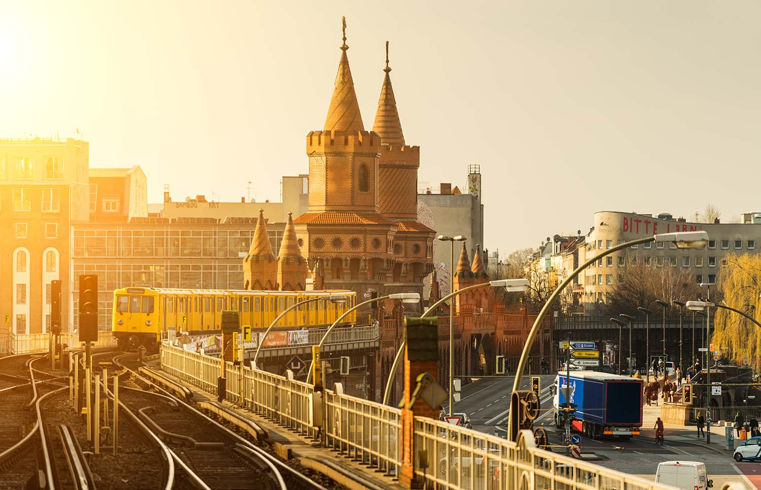 Oberbaumbrücke in Berlin-Kreuzberg mit U-Bahn-Zug auf den Gleisen bei tiefstehender Sonne.