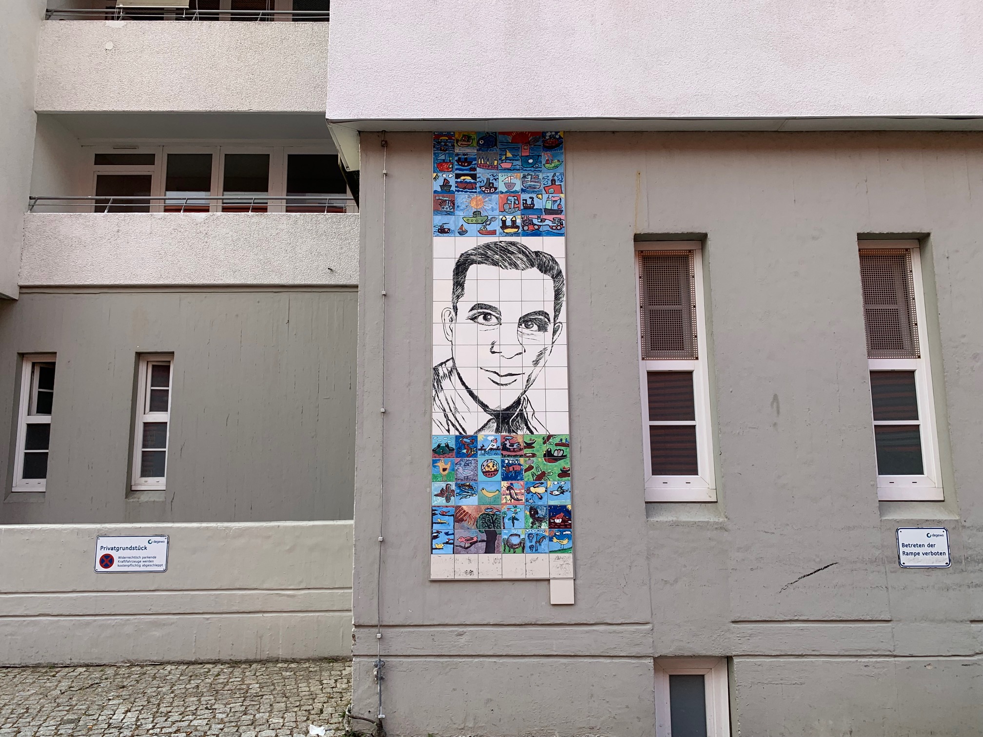 Ein Fliesenbild an einem Gebäude, in dem das Gesicht von Joachim Gottschalk im vereinfachten, gezeichneten Stil zu sehen ist.