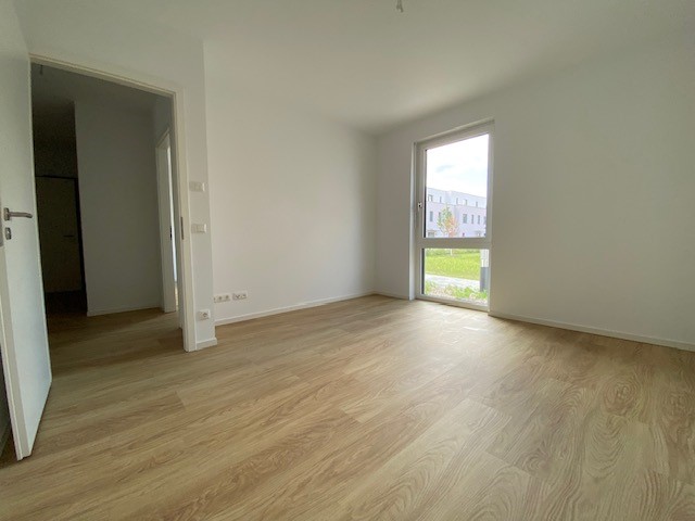 Innenansicht degewo-Neubau Fürstenwalder Allee 324/326: leeres Zimmer mit Blick in den Flur durch die geöffnete Tür.