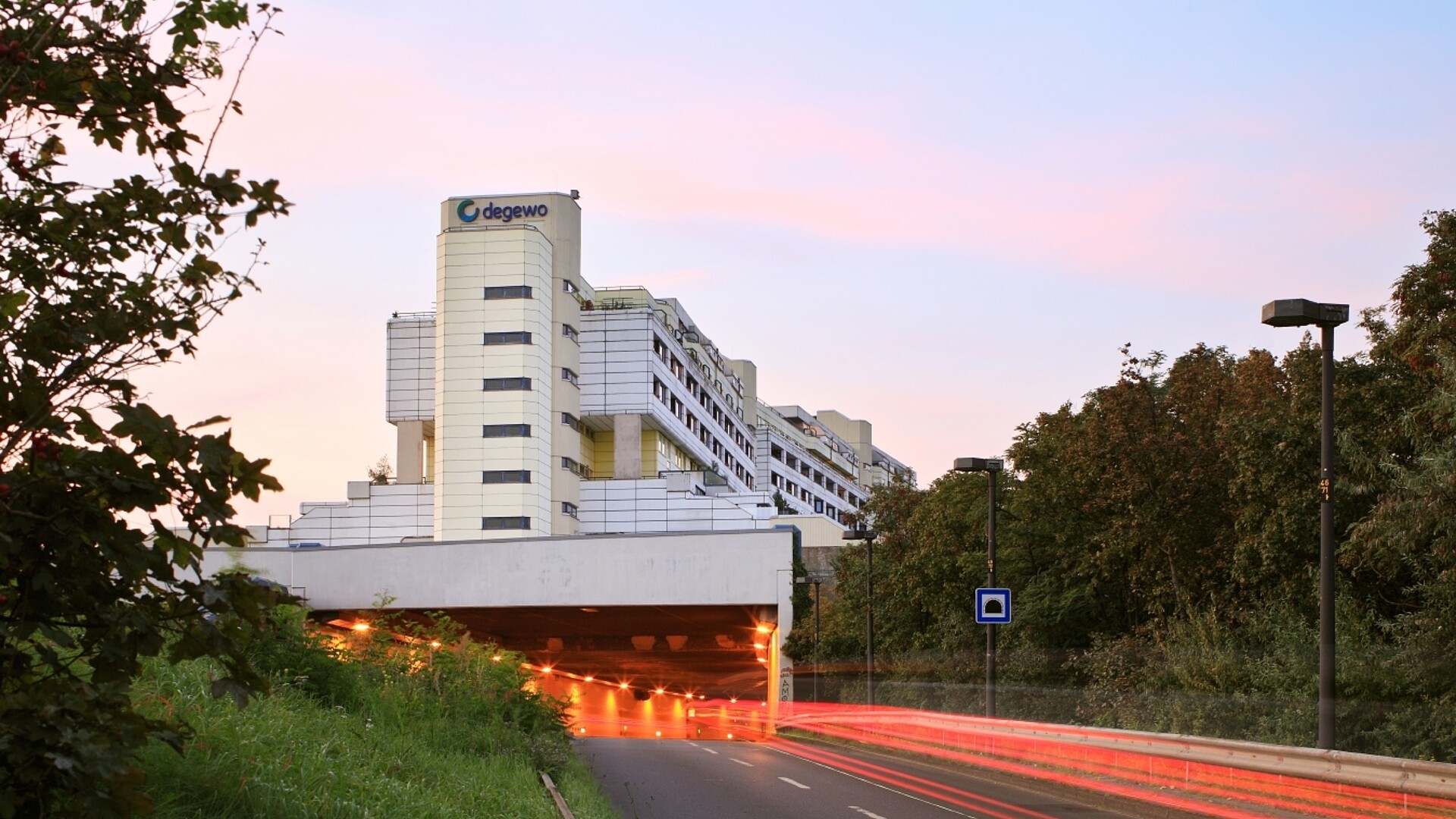Blick auf einen großen Wohnkomplex mit weißen Platten an den Außenwänden und der Aufschrift degewo