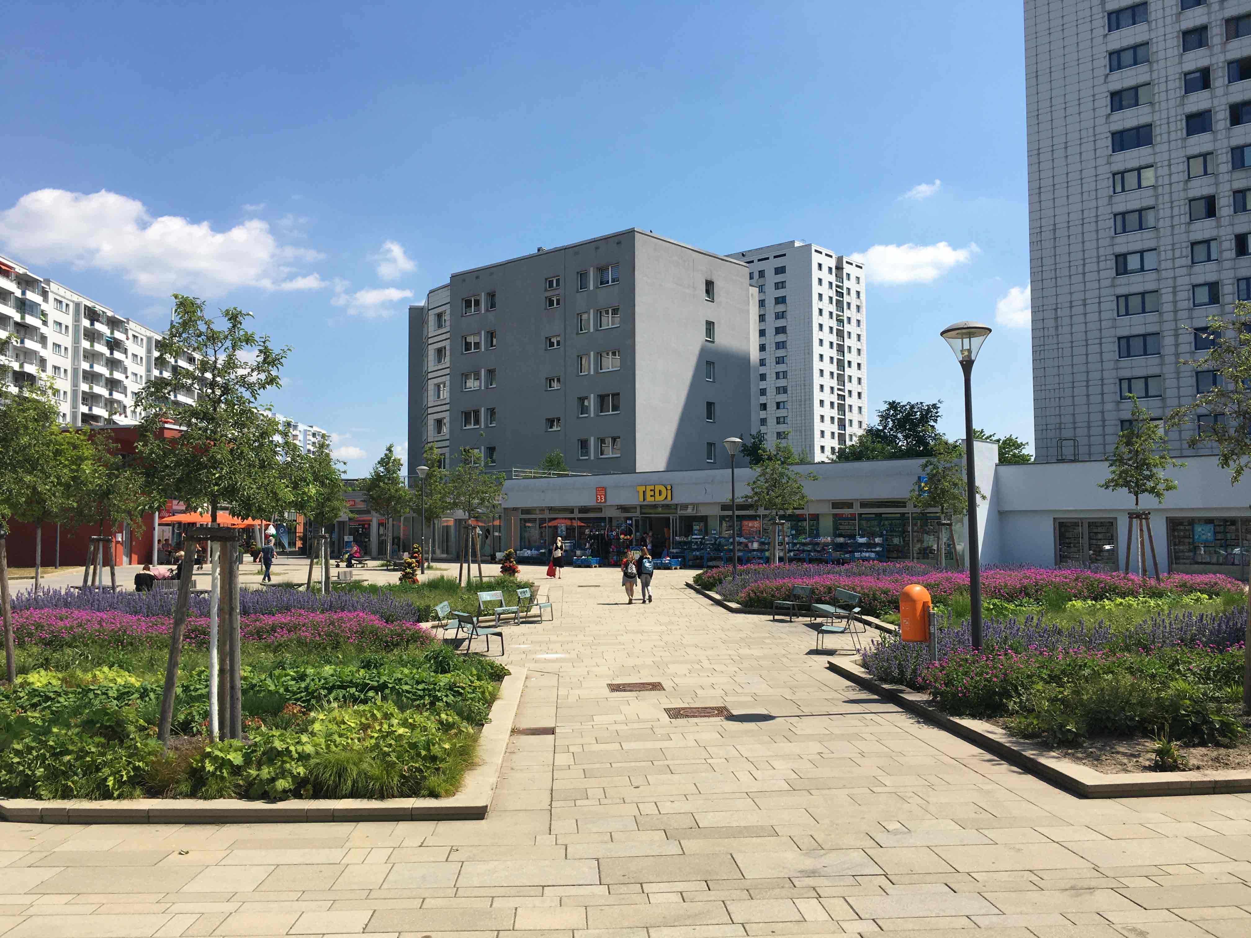 Weg aus Pflastersteinen mit Grünflächen und Geschäften